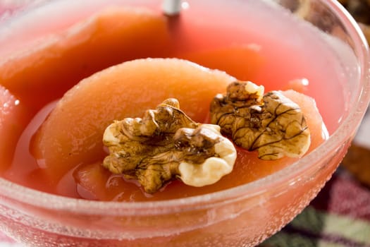 Apple compote with dried fruits in the cup on wooden table with decorative wallnuts
