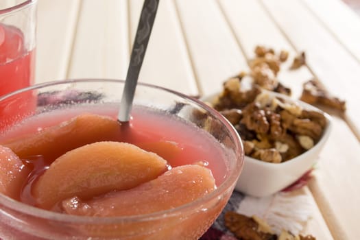 Apple compote with dried fruits in the cup on wooden table with decorative wallnuts