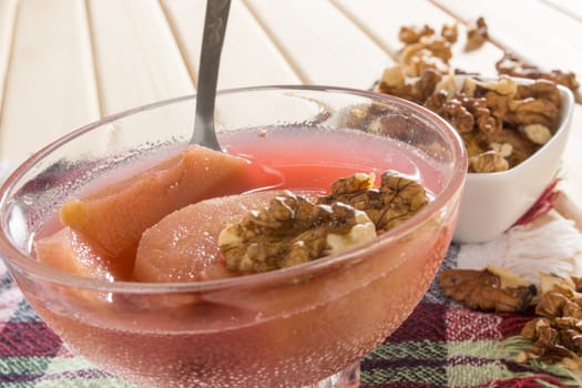 Apple compote with dried fruits in the cup on wooden table with decorative wallnuts