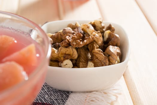 Apple compote with dried fruits in the cup on wooden table with decorative wallnuts