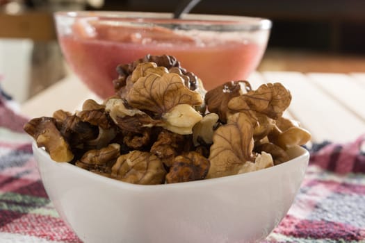 Apple compote with dried fruits in the cup on wooden table with decorative wallnuts