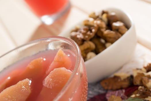 Apple compote with dried fruits in the cup on wooden table with decorative wallnuts