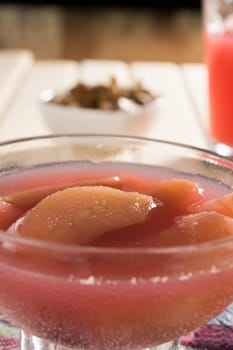 Apple compote with dried fruits in the cup on wooden table with decorative wallnuts