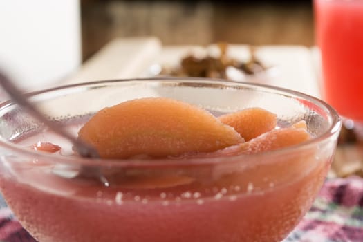 Apple compote with dried fruits in the cup on wooden table with decorative wallnuts