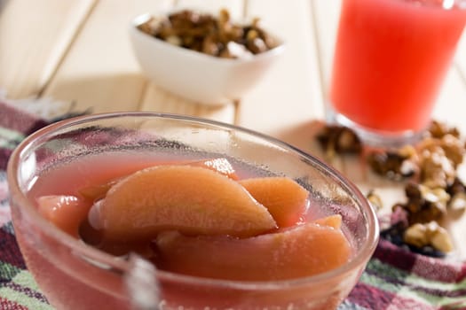Apple compote with dried fruits in the cup on wooden table with decorative wallnuts