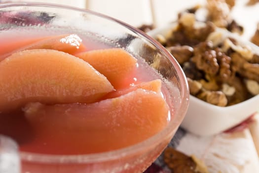 Apple compote with dried fruits in the cup on wooden table with decorative wallnuts