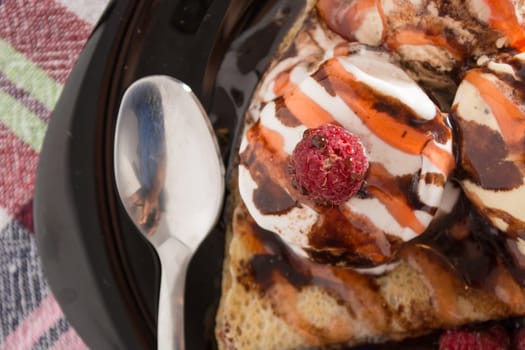 Fresh, golden pancakes with fruit and cream on a black plate with blurred background
