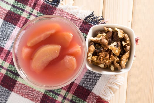 Apple compote with dried fruits in the cup on wooden table with decorative wallnuts