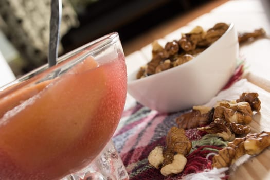 Apple compote with dried fruits in the cup on wooden table with decorative wallnuts