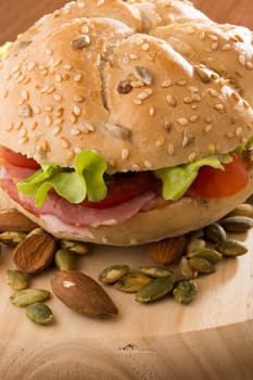 Sandwich with fresh smoked meat, cheese, lettuce and tomato with homemade ketchup arranged with almond and pumpkin seeds
