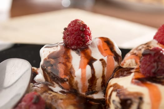 Fresh, golden pancakes with fruit and cream on a black plate with blurred background