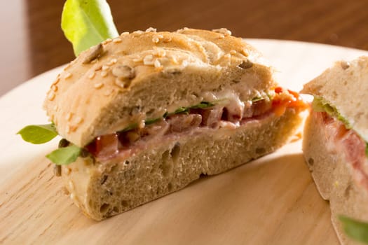 Sandwich with fresh smoked meat, cheese, lettuce and tomato with homemade ketchup sliced in half