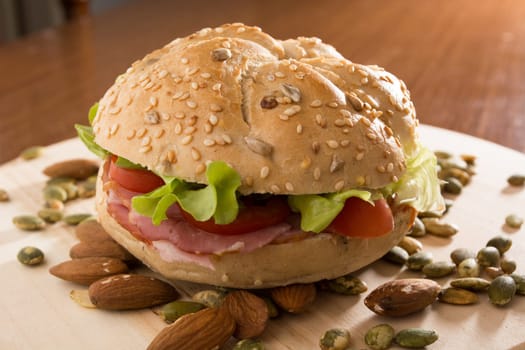 Sandwich with fresh smoked meat, cheese, lettuce and tomato with homemade ketchup arranged with almond and pumpkin seeds