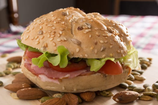 Sandwich with fresh smoked meat, cheese, lettuce and tomato with homemade ketchup arranged with almond and pumpkin seeds