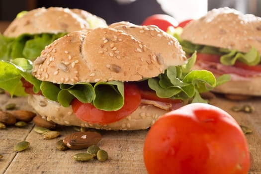 Sandwiches with fresh smoked meat, cheese, lettuce and tomato with homemade ketchup arranged with almond and pumpkin seeds