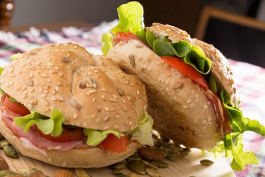 Sandwich with fresh smoked meat, cheese, lettuce and tomato with homemade ketchup arranged with almond and pumpkin seeds