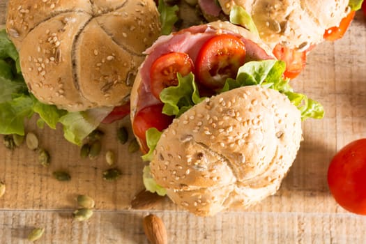 Sandwiches with fresh smoked meat, cheese, lettuce and tomato with homemade ketchup arranged with almond and pumpkin seeds