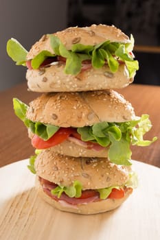 Three Sandwiches with fresh smoked meat, cheese, lettuce and tomato with homemade ketchup stacked one on another