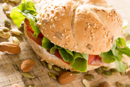 Sandwich with fresh smoked meat, cheese, lettuce and tomato with homemade ketchup arranged with almond and pumpkin seeds