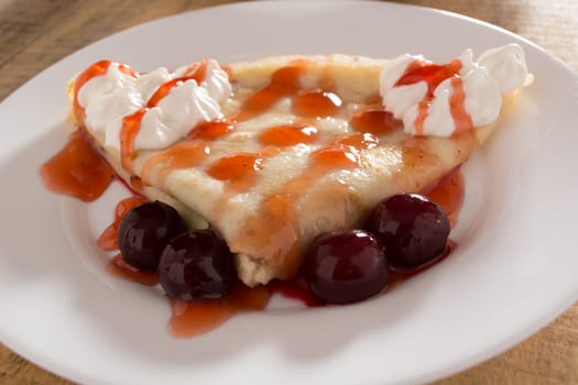 Fresh pancakes with cherry arranged on wooden table