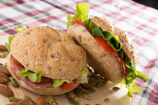Sandwich with fresh smoked meat, cheese, lettuce and tomato with homemade ketchup arranged with almond and pumpkin seeds
