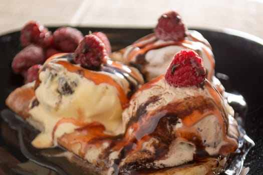 Fresh, golden pancakes with fruit and cream on a black plate with blurred background