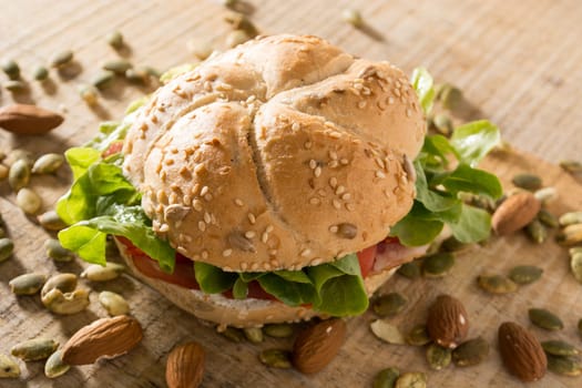 Sandwich with fresh smoked meat, cheese, lettuce and tomato with homemade ketchup arranged with almond and pumpkin seeds
