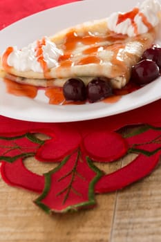 Fresh pancakes with cherry arranged on wooden table