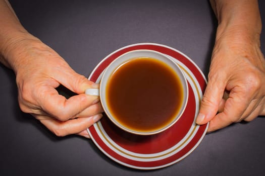 The female hands of an old woman with a cup of coffee
