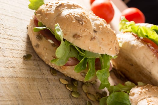 Sandwiches with fresh smoked meat, cheese, lettuce and tomato with homemade ketchup arranged with almond and pumpkin seeds