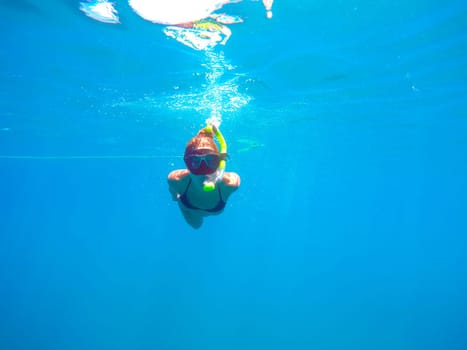 Portrait of a yound woman swimming underwater in the clean blue sea of Limassol, Cyprus. View of snorkeling tube, mask, bikini of free diver near the surface of the water.