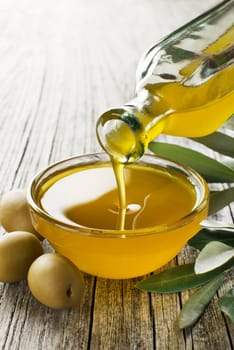 Bottle pouring virgin olive oil in a bowl close up