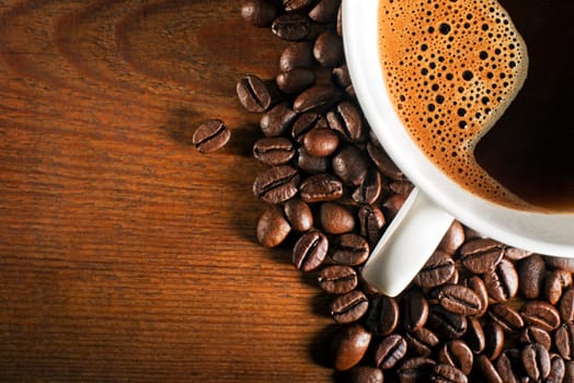 Coffee cup and beans on a wooden background.