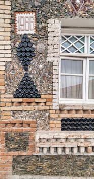 Glass bottle decoration on the Bottle House in Ganja, Azerbaijan - a triangular shapes made from stacked bottles, beside wooden antique window