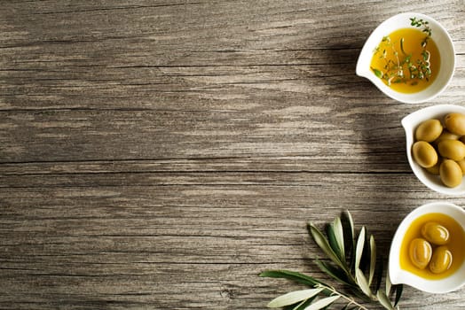 Olive oil with fresh herbs on wooden background.