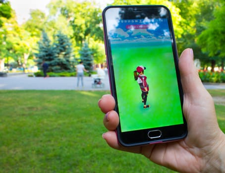 Dnipropetrovsk, Ukraine - July 23, 2016: The female hand holding phone with game Pokemon GO - a free-to-play augmented reality mobile game developed by Niantic for iOS and Android devices.