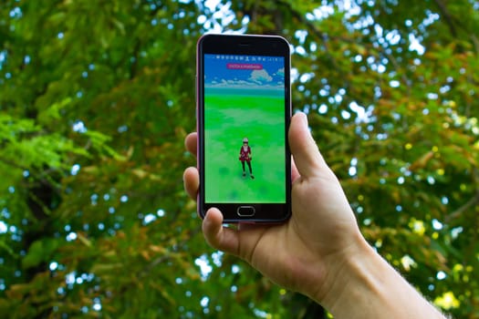 Dnipropetrovsk, Ukraine - July 23, 2016: The female hand holding phone with game Pokemon GO - a free-to-play augmented reality mobile game developed by Niantic for iOS and Android devices.