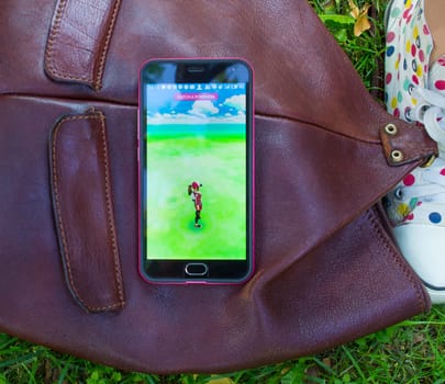 Dnipro, Ukraine - July 23, 2016: The hit augmented reality smartphone app Pokemon GO shows a Pokemon encounter overlain in park in the real world.