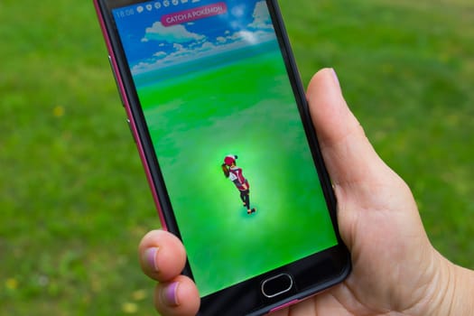 Dnipropetrovsk, Ukraine - July 23, 2016: The female hand holding phone with game Pokemon GO - a free-to-play augmented reality mobile game developed by Niantic for iOS and Android devices.