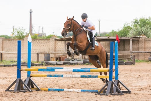 Volgograd, Russia - June 19, 2016: The athlete performs a jump on a horse through the barrier on the jumping competition