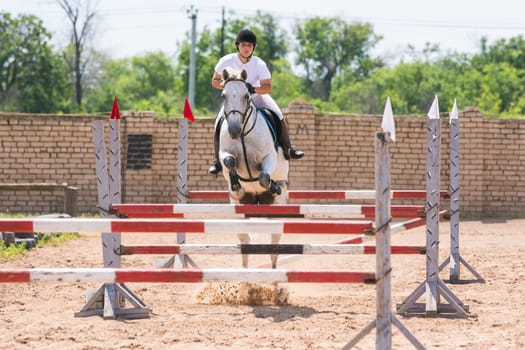 Volgograd, Russia - June 19, 2016: The sportswoman on a horse show jumping phase passes with multiple barriers