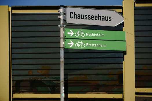 Traffic signs for cycle paths as well as information signs stand in front of a soundproofing wall.