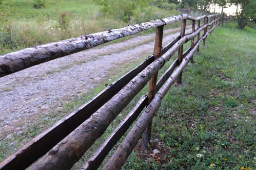 Old rural wooden fence on the road troug the woods