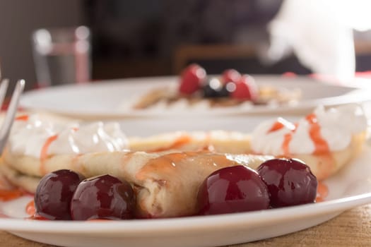 Fresh pancakes with cherry arranged on wooden table