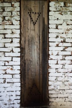 Rustic smokehouse door on white brick wall