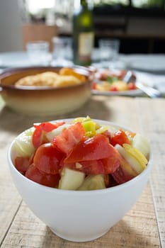 Cucumber and tomato sallad in the white dish on rustic wooden table