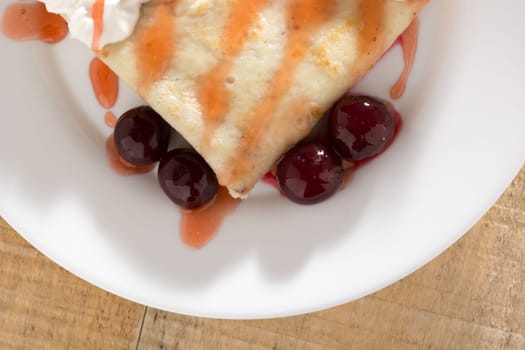 Fresh pancakes with cherry arranged on wooden table