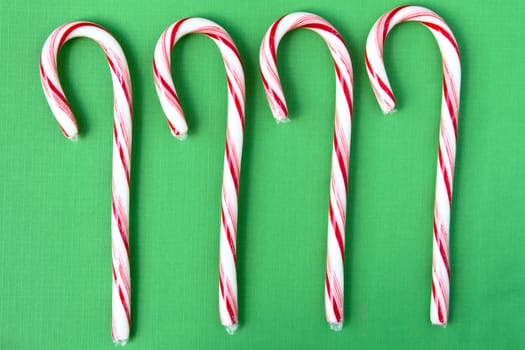 Four candy canes on green background.