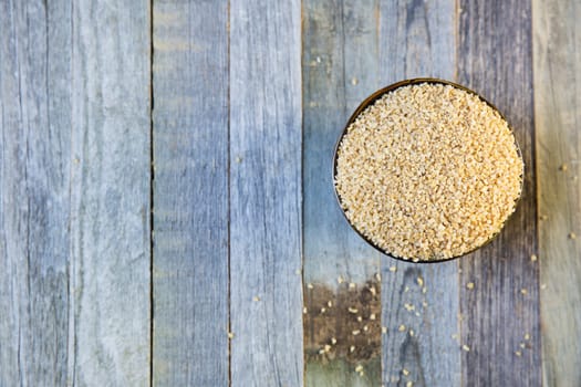 Bowl of bulgur and rolled oats in a row viewed from above on an old wooden table, with copy space