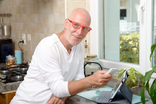 a middle-aged man with a mobile phone in his kitchen
